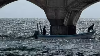 Trabajadores de Pemex colocan barreras junto al muelle para contener manchas de combustible