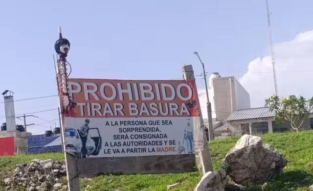 Singular letrero con cabeza advierte: “Prohibido tirar basura”