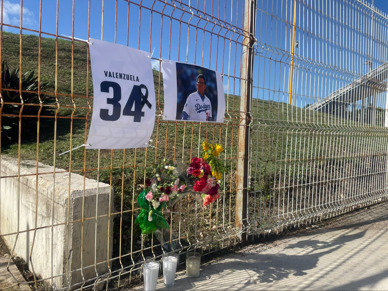 Fuera del estadio se puede encontrar una foto del jugador con flores y velas Fuera del estadio se puede encontrar una foto del jugador con flores y velas