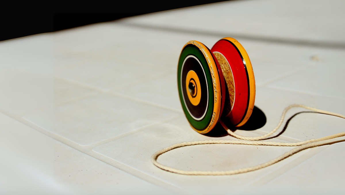 Un disco de madera o plástico con un hilo enrollado, que se hace subir y bajar repetidamente Un disco de madera o plástico con un hilo enrollado, que se hace subir y bajar repetidamente