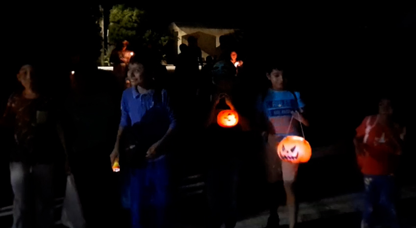 Los niños caminan en grupos con calabazas, velas y veladoras para iluminar sus caminos Los niños caminan en grupos con calabazas, velas y veladoras para iluminar sus caminos