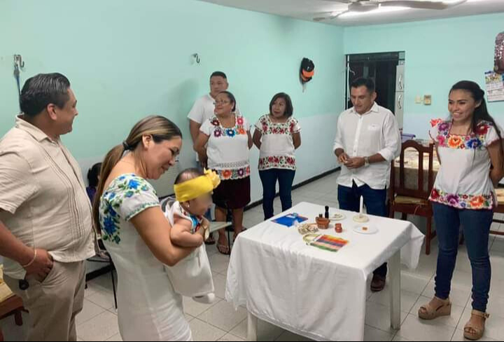 El padrino y la madrina dan nueve vueltas alrededor de la mesa, entregando al niño objetos simbólicos que representan sus futuras habilidades El padrino y la madrina dan nueve vueltas alrededor de la mesa, entregando al niño objetos simbólicos que representan sus futuras habilidades