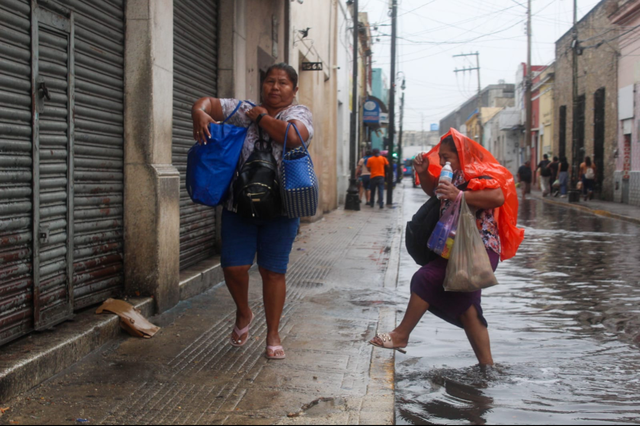 Mujer cruza la calle, a pesar de la inundación en Mérida Mujer cruza la calle, a pesar de la inundación en Mérida