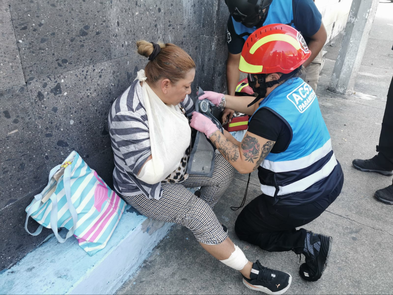 Paramédicos atienden a la mujer herida con vendajes en brazo y pierna Paramédicos atienden a la mujer herida con vendajes en brazo y pierna