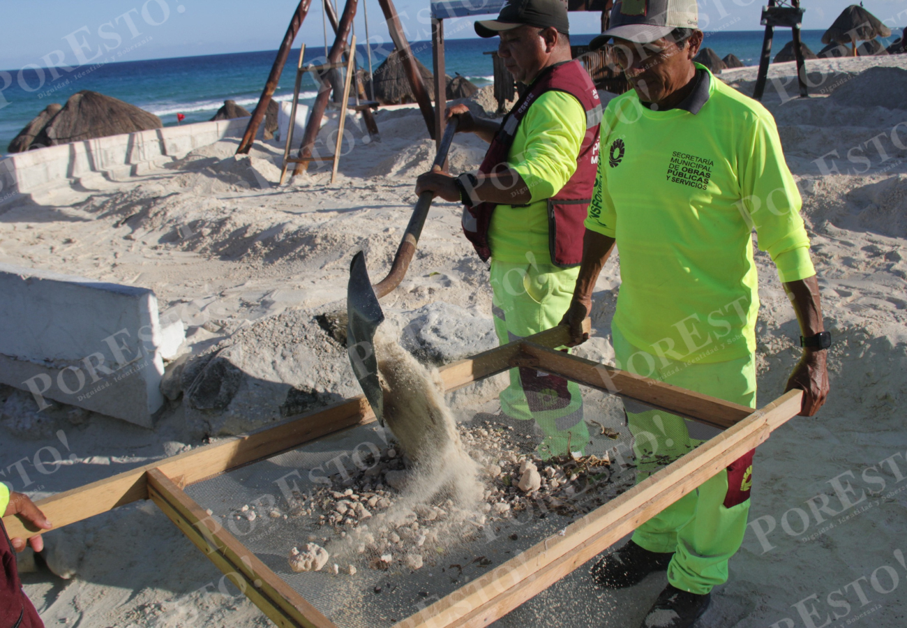 Los trabajadores de limpieza se encargan de limpiar la arena filtrándola para extraer los residuos Los trabajadores de limpieza se encargan de limpiar la arena filtrándola para extraer los residuos