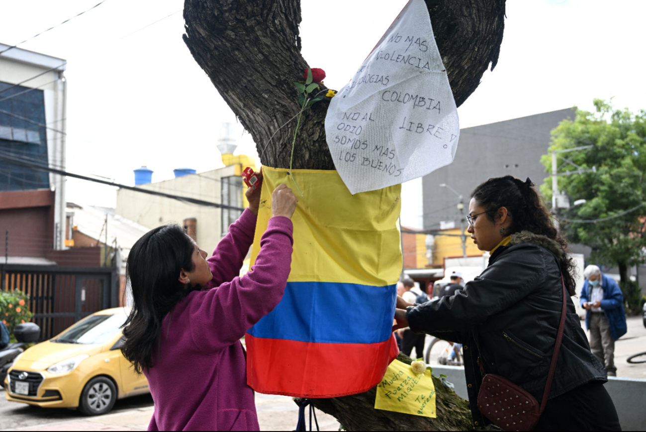 Mujeres sostienen una bandera colombiana en el lugar donde el senador Miguel Uribe Turbay fue herido de bala. Mujeres sostienen una bandera colombiana en el lugar donde el senador Miguel Uribe Turbay fue herido de bala.