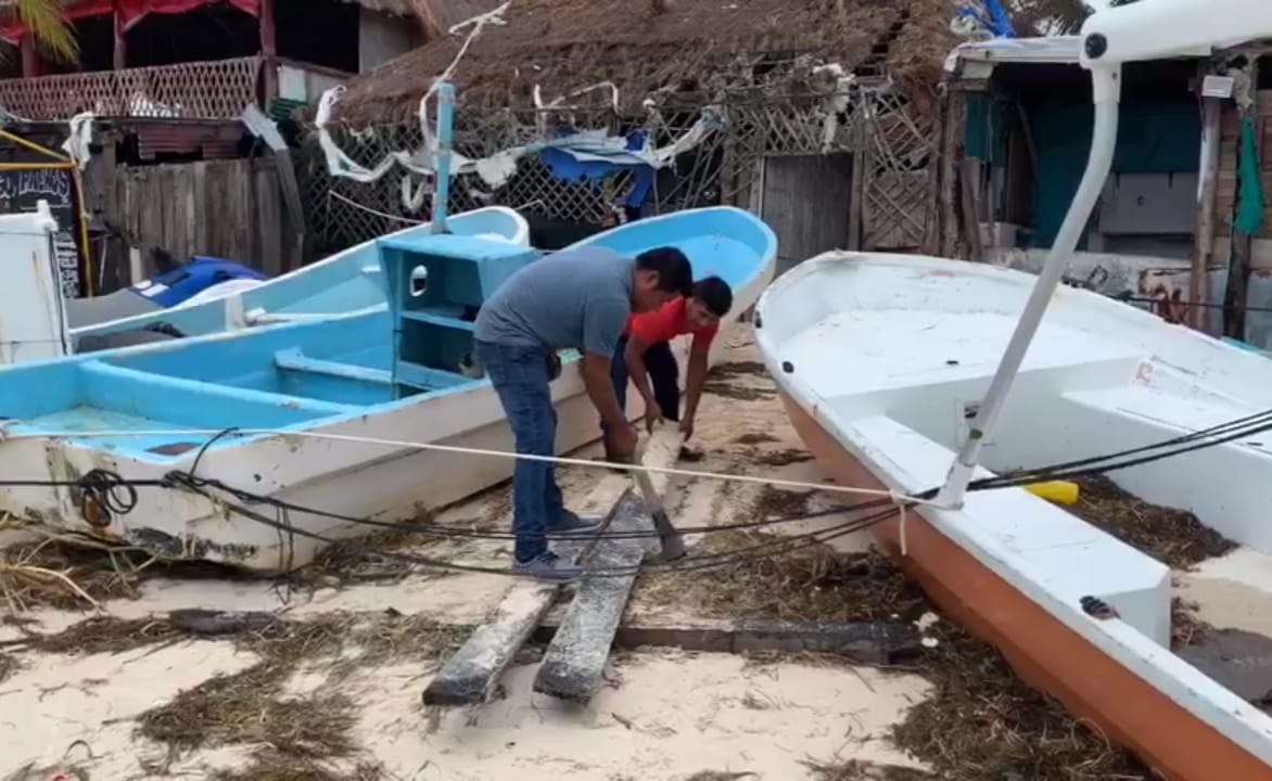 Hombres de mar recuperan sus herramientas que estaban enterradas en la arena. Foto: Karla Cauich. Hombres de mar recuperan sus herramientas que estaban enterradas en la arena. Foto: Karla Cauich.