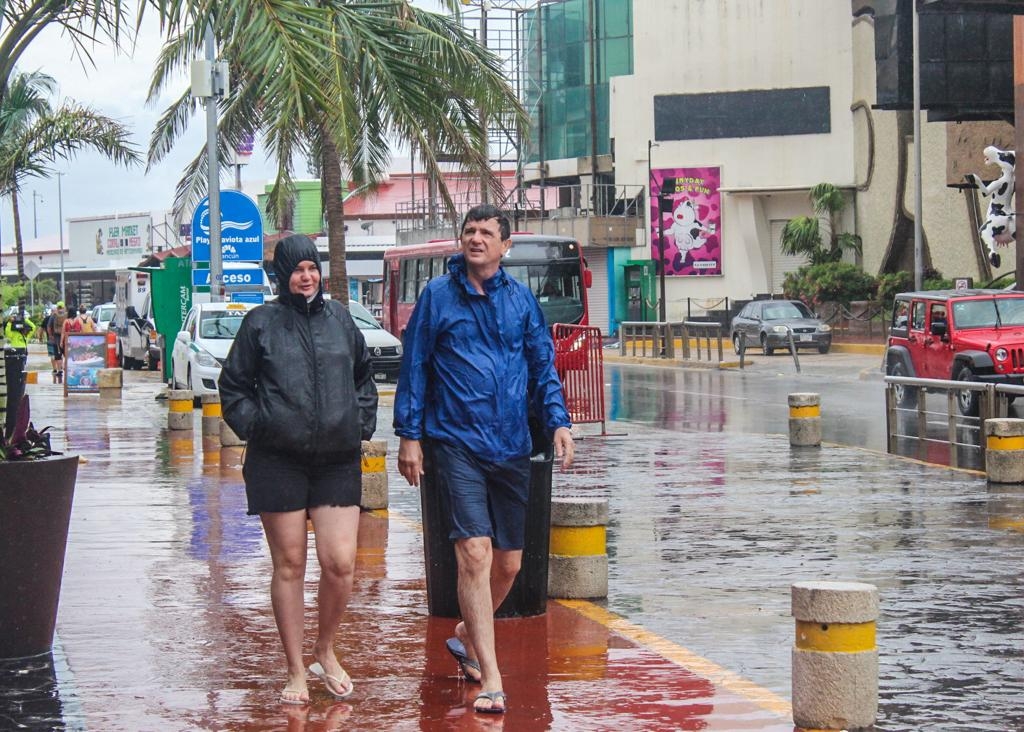 En la Zona Hotelera se observó a grupos de turistas con impermeables y paraguas o entrando a las plazas comerciales