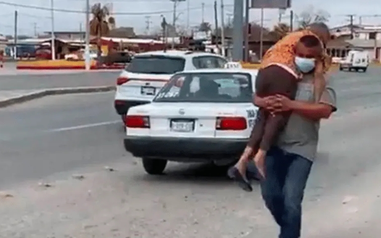 Un hombre carga a su mamá para llevarla a vacunar contra el COVID-19