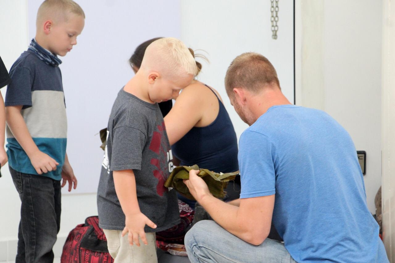 Familia de turistas extranjeros come tamales en el aeropuerto de Cancún