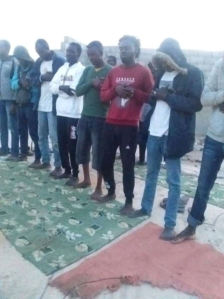 migrantes rezando antes de subierse a una precaria embarcación para tratar de llegar de Libia a Europa