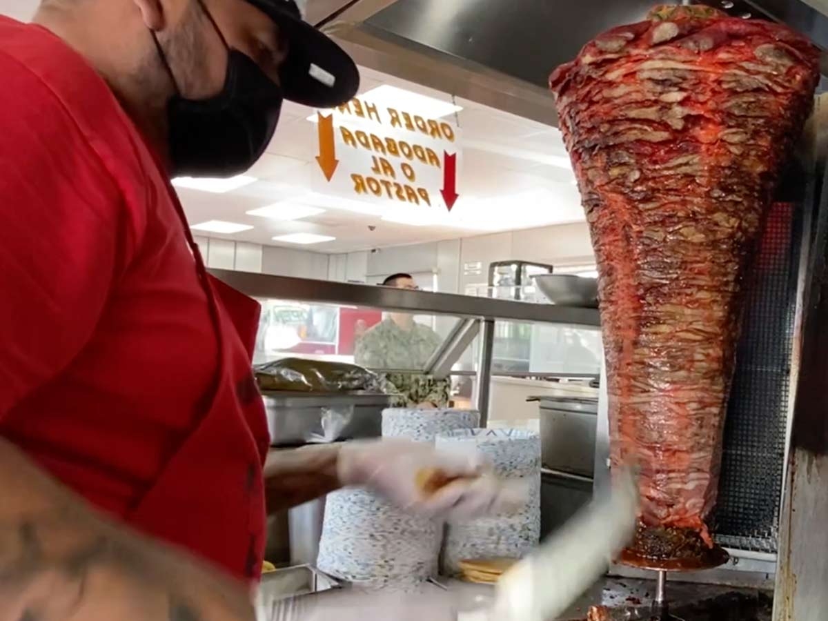Taquero en San Diego prepara una orden de pastor Taquero en San Diego prepara una orden de pastor