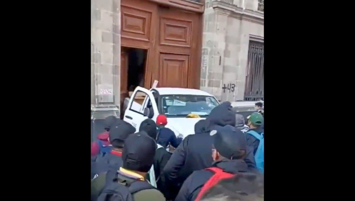 Un grupo de presuntos normalistas de Ayotzinapa derribó con una camioneta de la CFE una de las puertas de Palacio Nacional